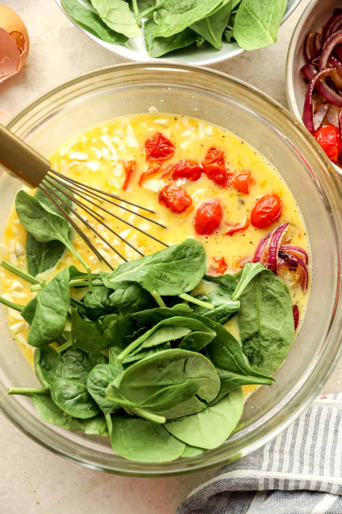 a bowl filled with egg, spinach, and tomato.