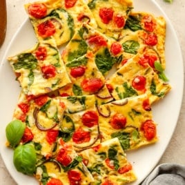 Overhead are squares of vegetable frittata on a white plate.