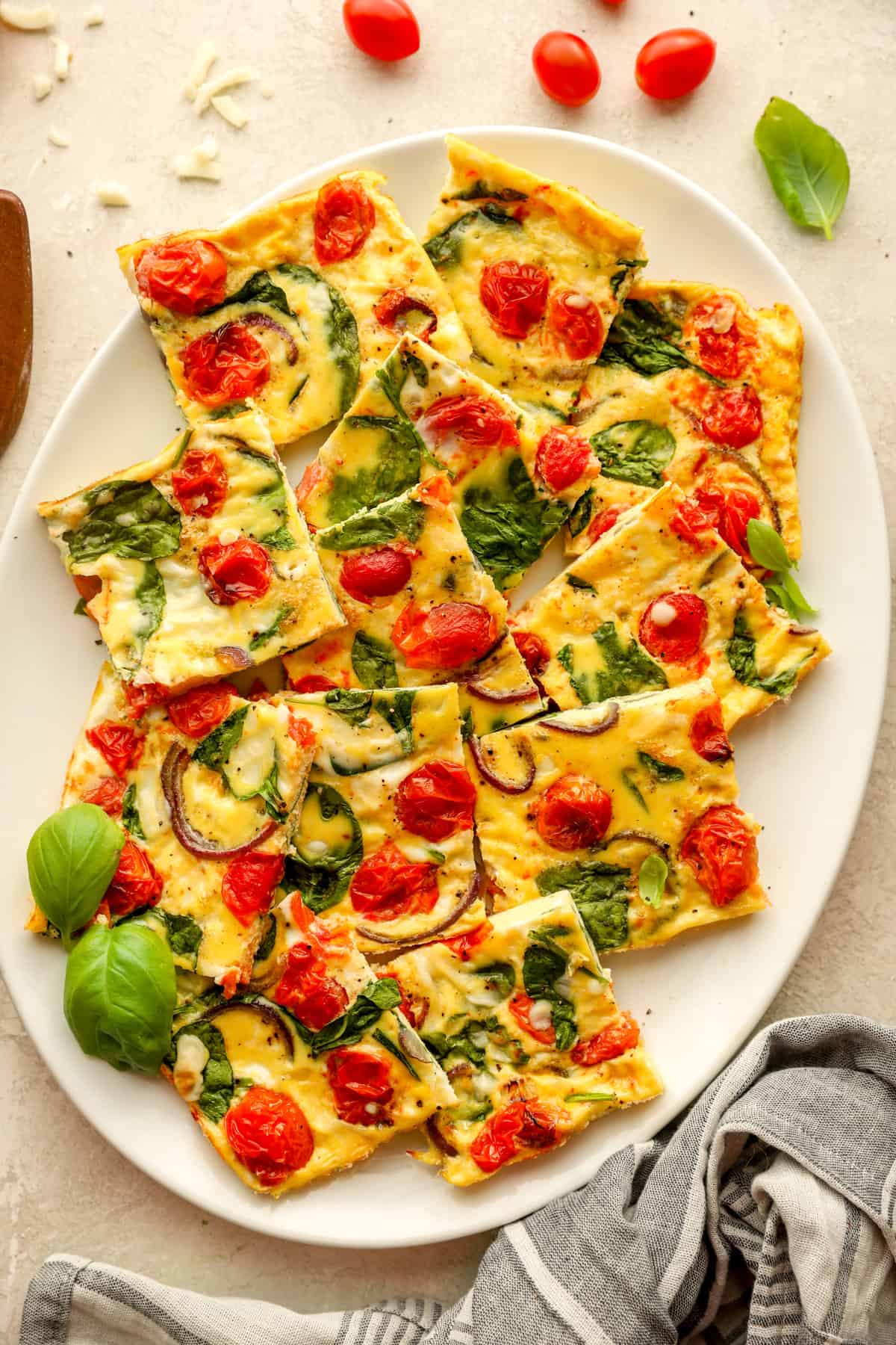overhead of squares of vegetable frittata on a white serving platter.