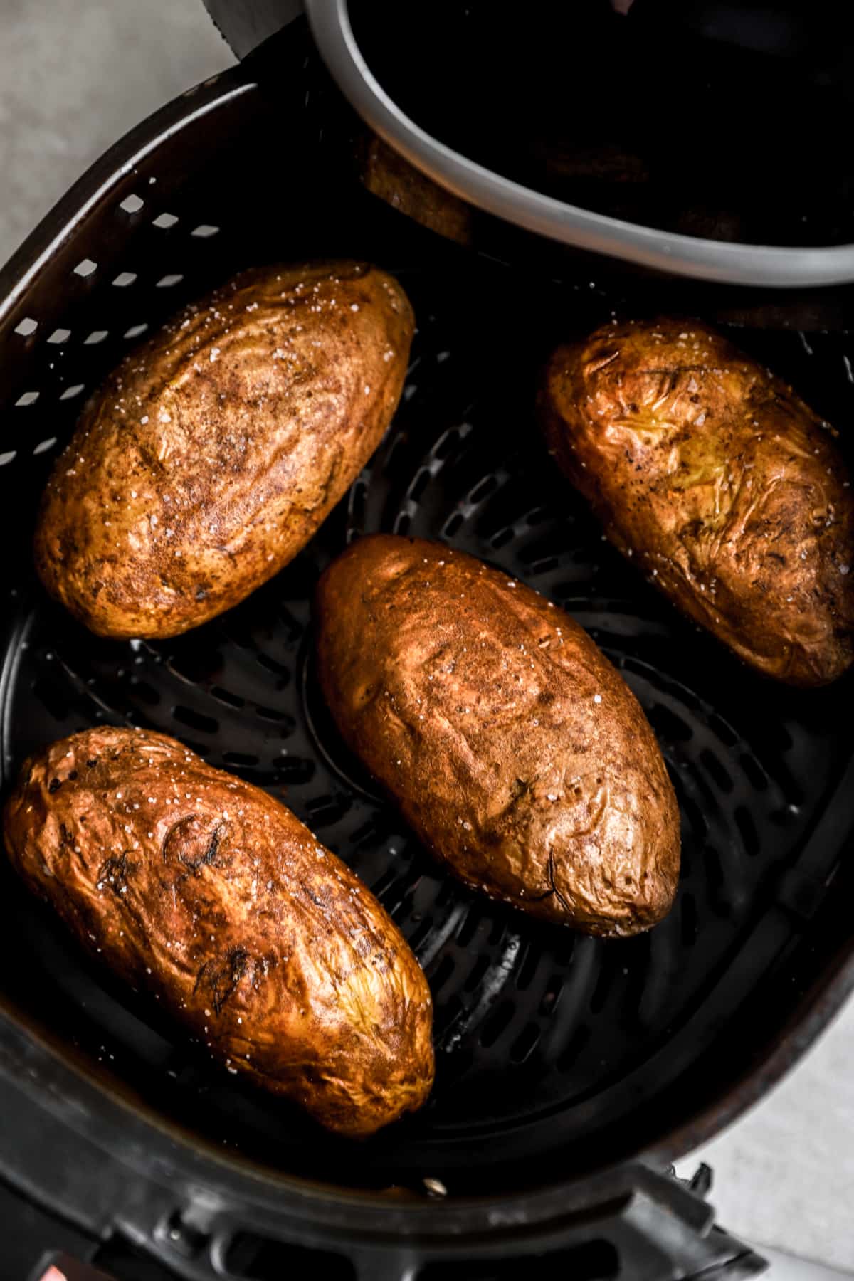 baked potatoes in an air fryer basket.