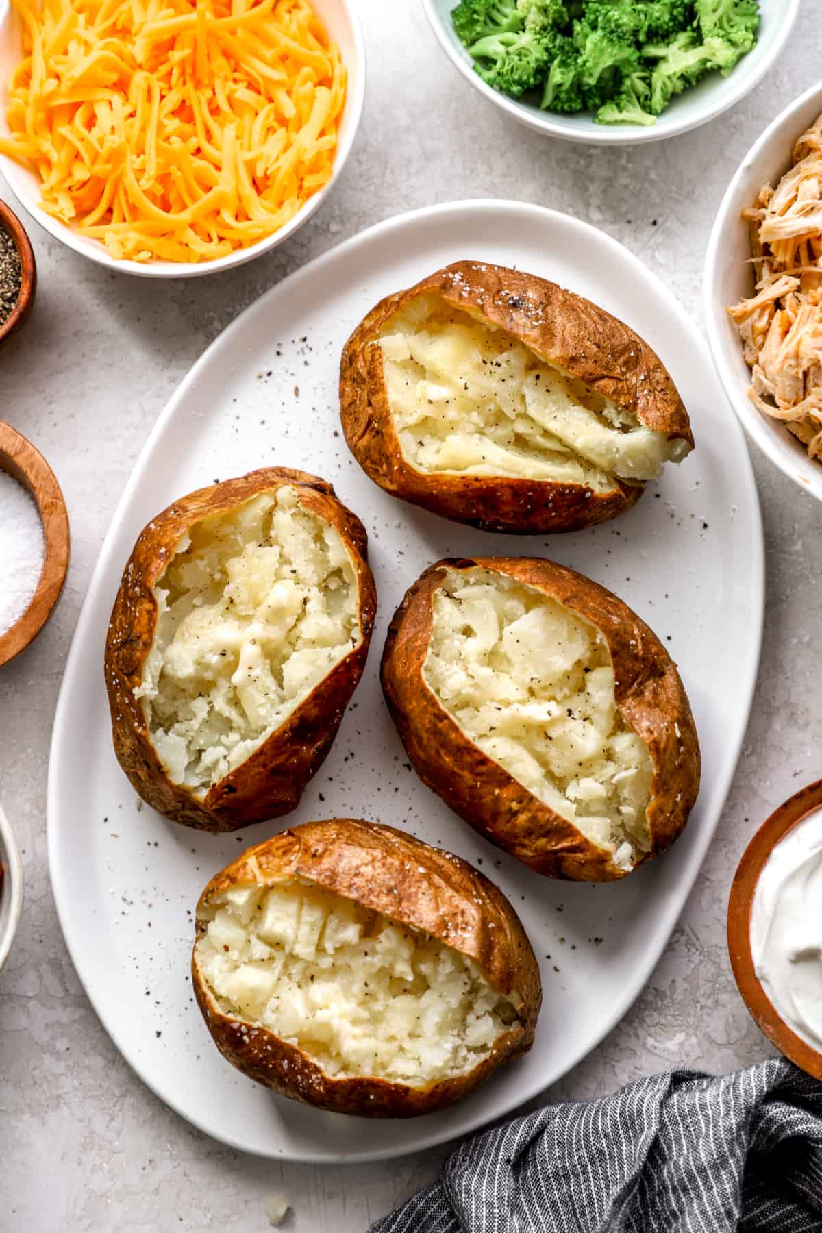 above image of four plain baked potatoes cut open on a plate.