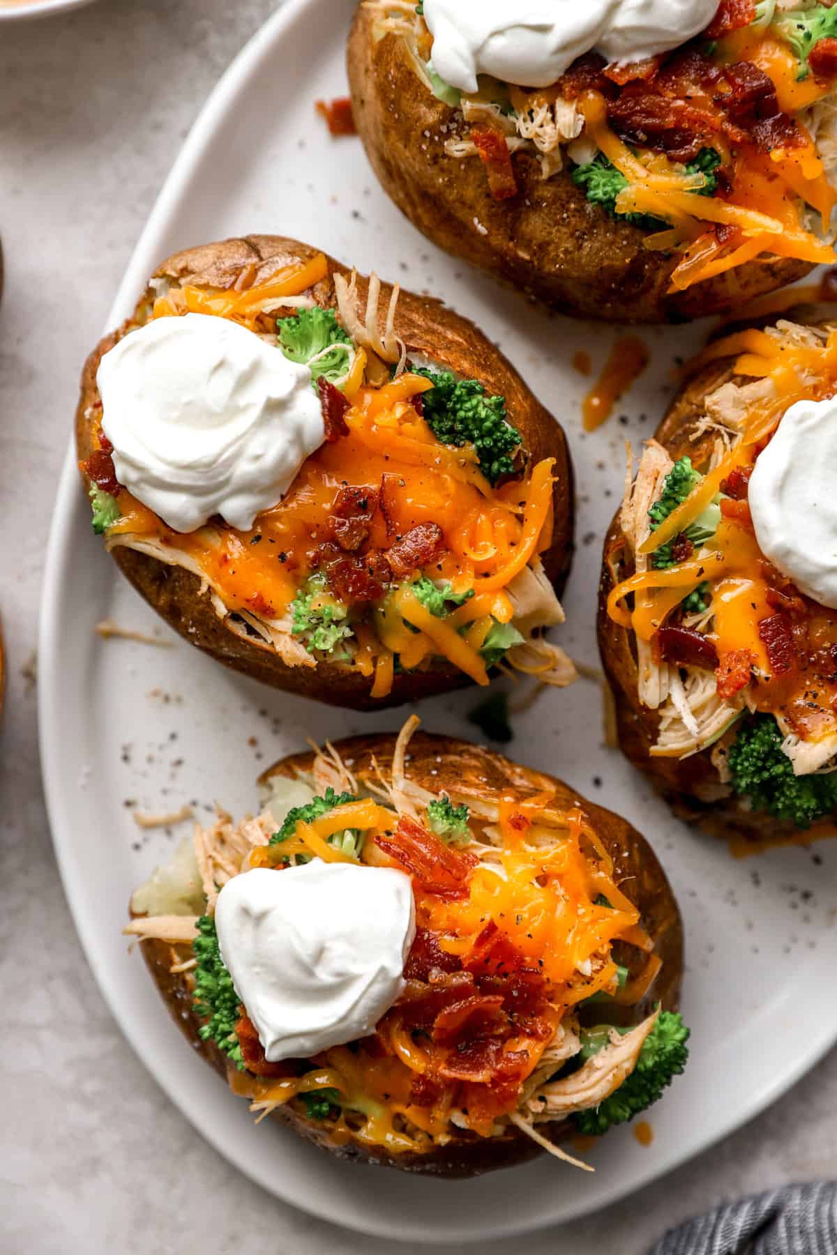 above image of air fryer baked potatoes on a plate loaded with toppings.
