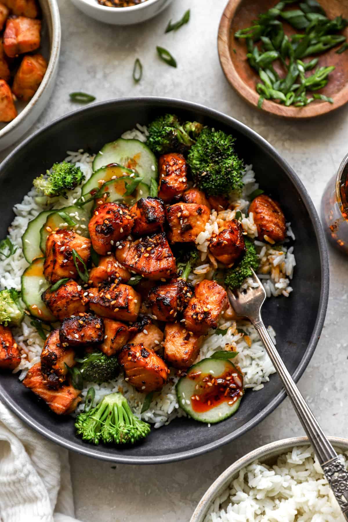 above image of air fried salmon bites on a plate over rice and topped with cucumber and broccoli.