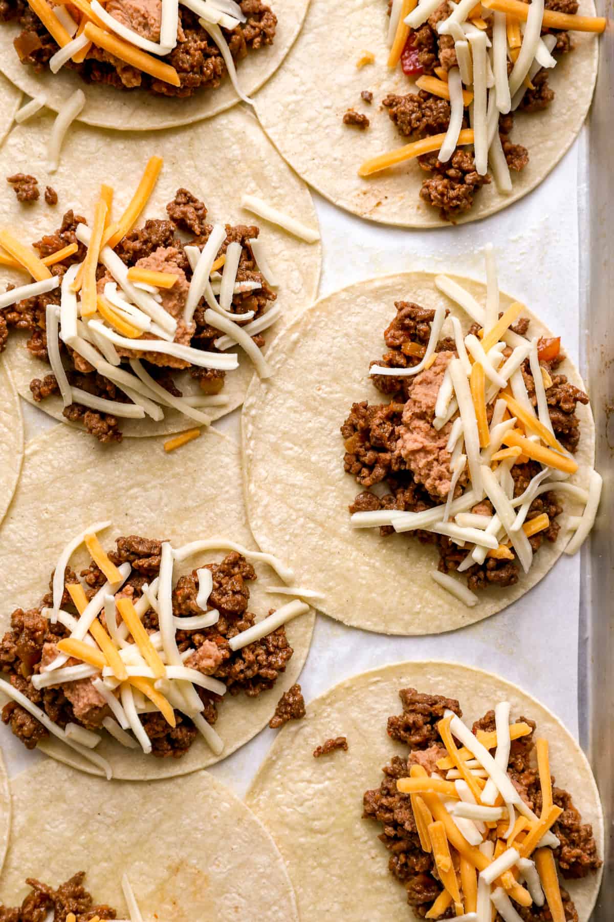 Tacos topped with ground beef, beans and cheese.