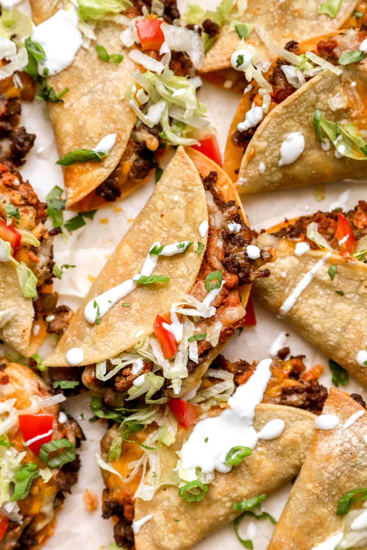 Close-up of assembled ground beef tacos, garnished with toppings.