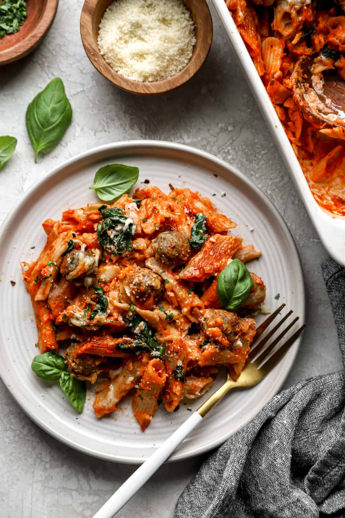 overhead image of baked pasta with spinach and meatballs on a plate with a fork.