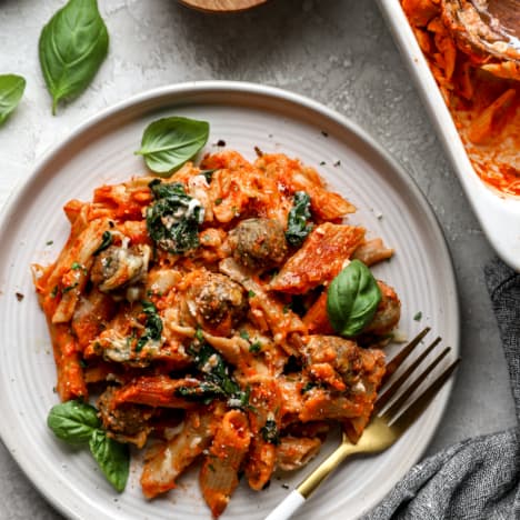 overhead image of baked pasta with spinach and meatballs on a plate with a fork.