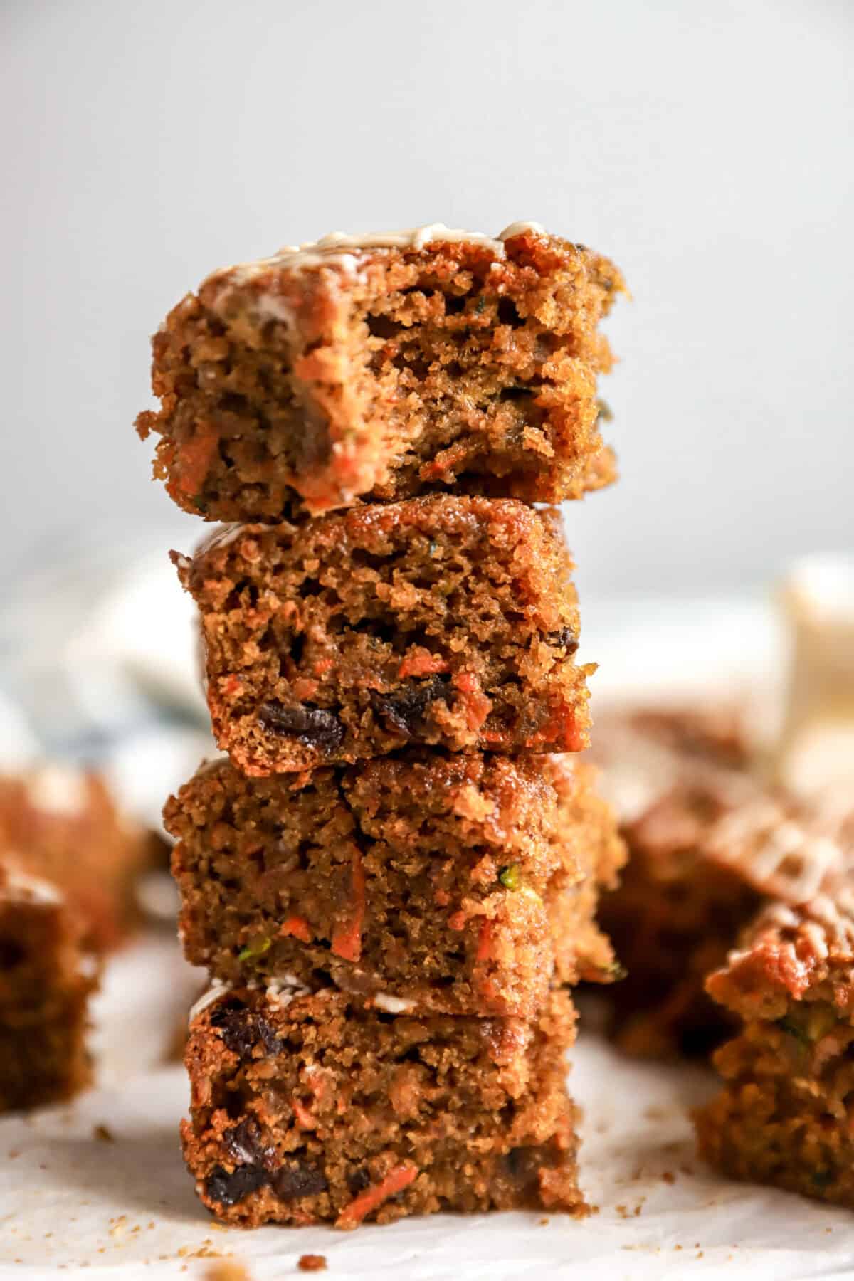 Carrot zucchini bars vertically stacked with a bite out of the top bar. 