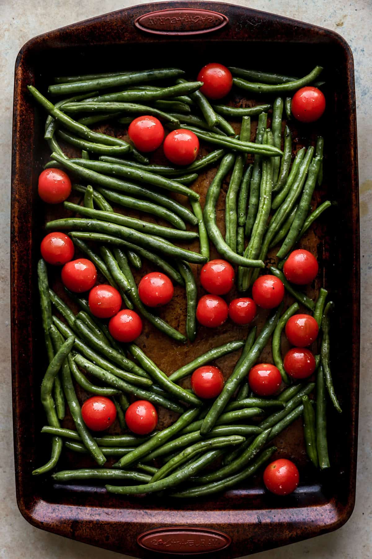 Green beans and cherry tomatoes on a baking sheet. 