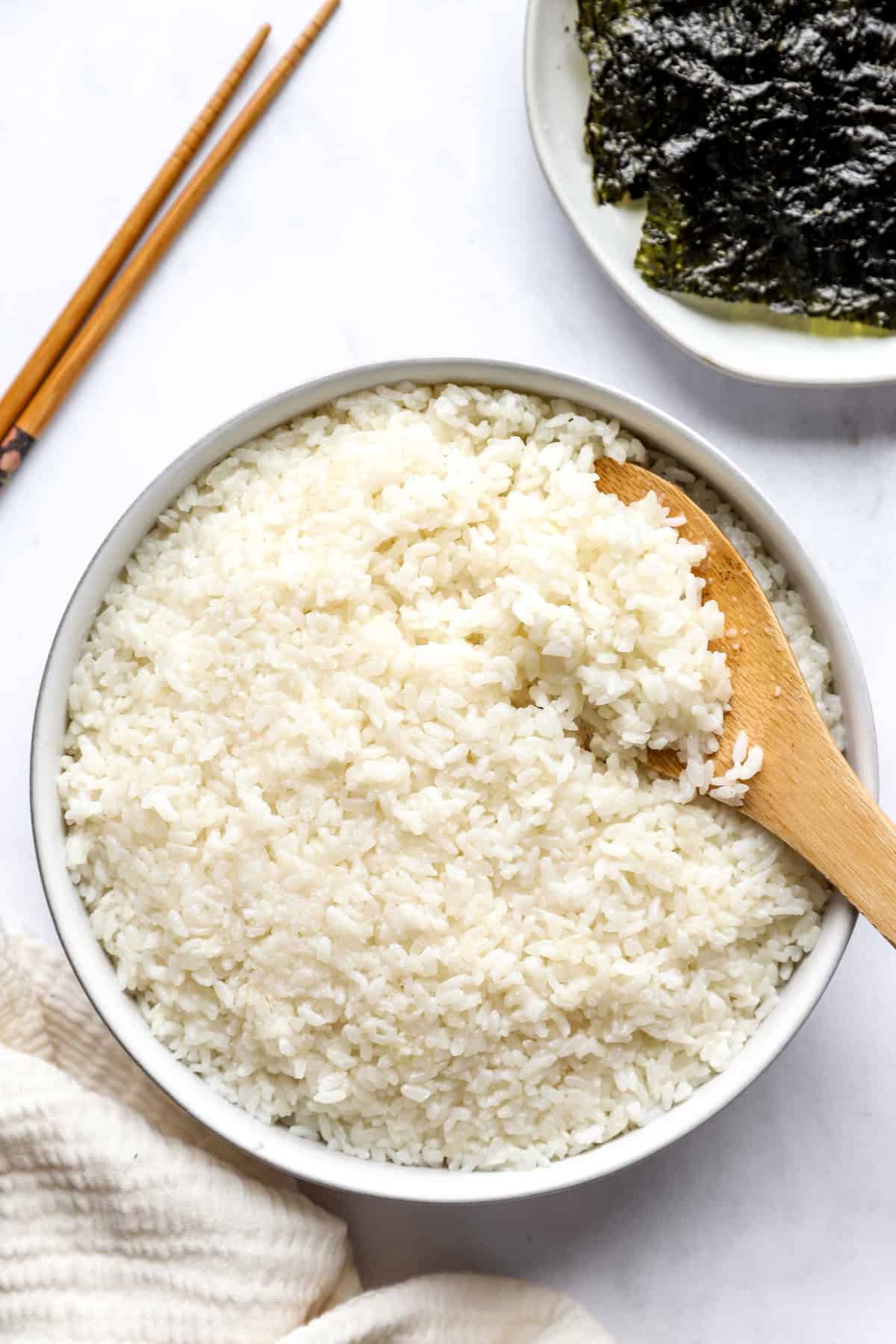 above image of a large bowl full of rice with a wooden spoon.