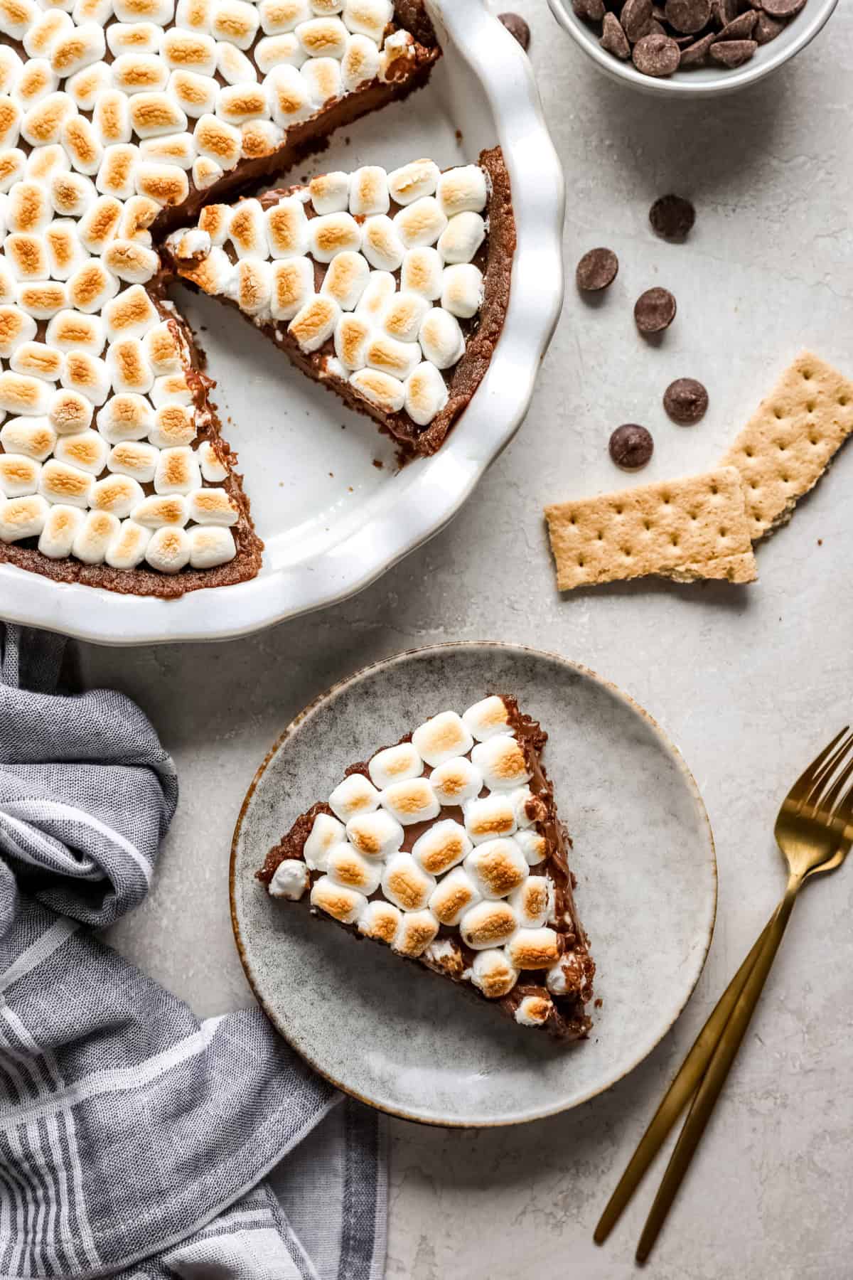 A slice of s'mores pie next to the rest of the pie in a pan. 