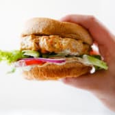 A hand holding a Moroccan chicken burger.