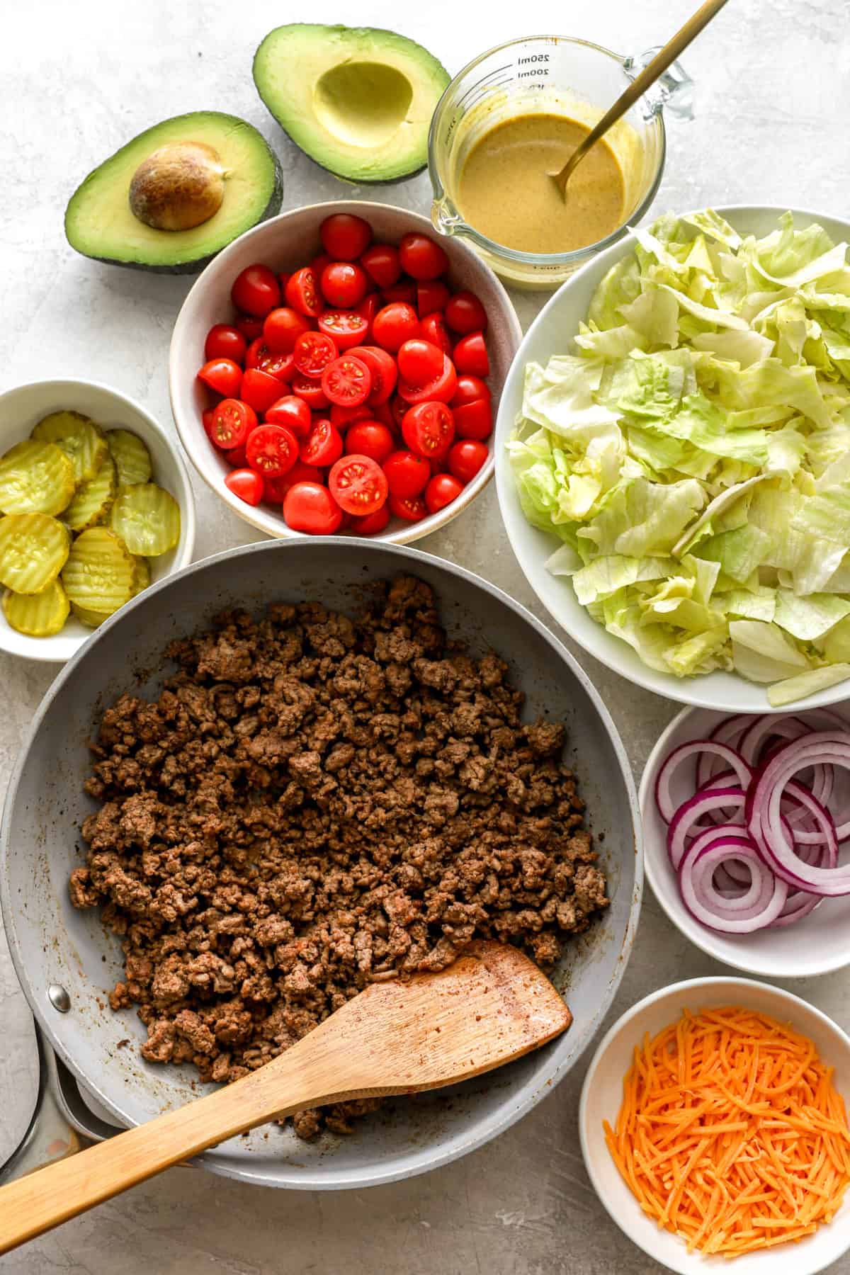 Bowls of ingredients to make a cheeseburger salad. 