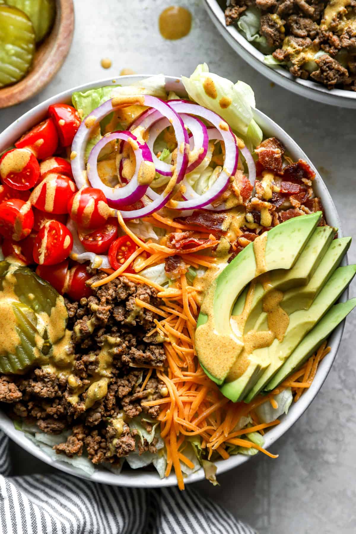 Overhead image of a cheeseburger salad topped with mustard dressing. 