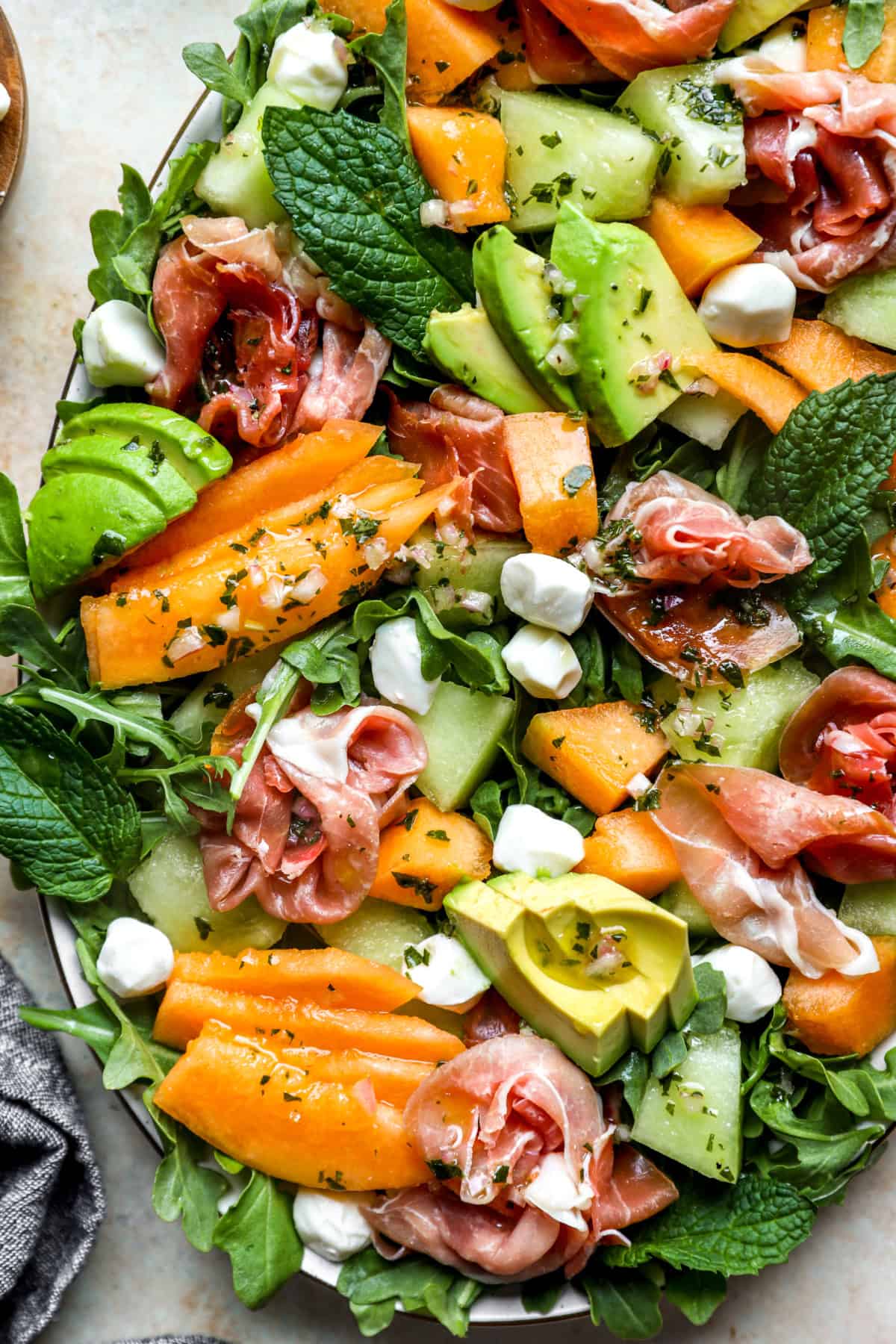 Close up image of a platter of melon and prosciutto salad. 