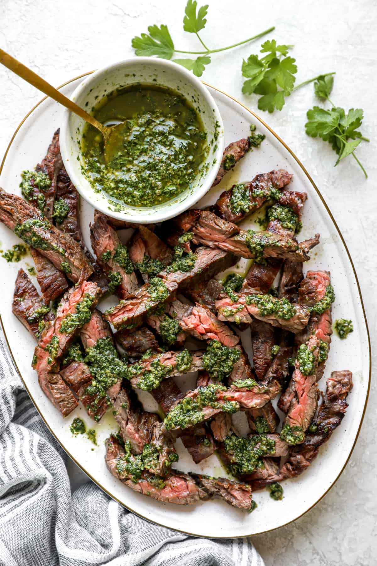 A platter of grilled skirt steak topped with Italian salsa verde. 