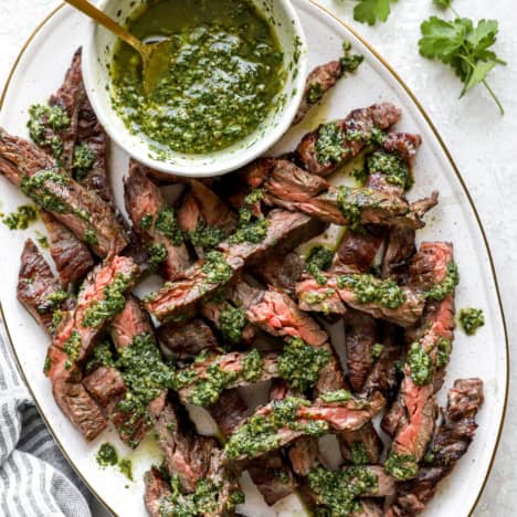 A platter of grilled skirt steak topped with Italian salsa verde.