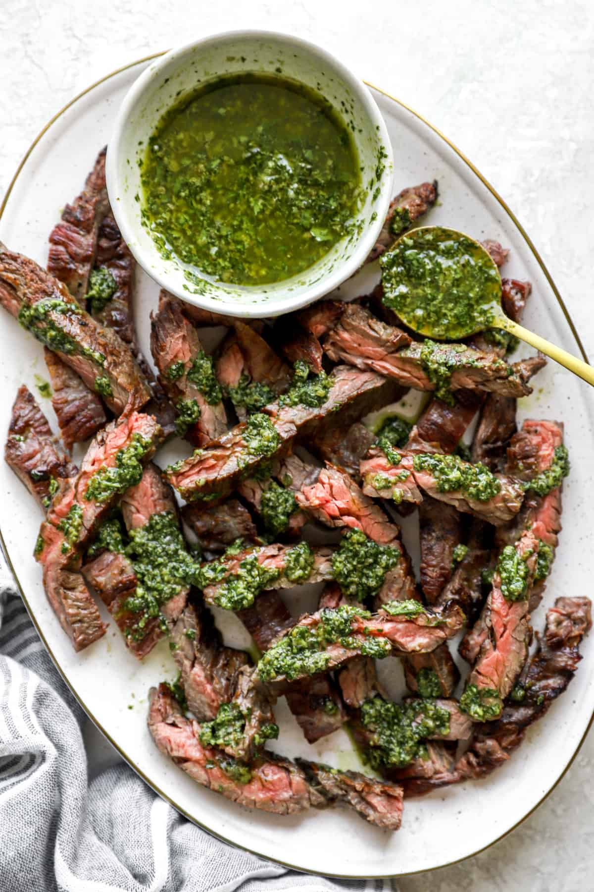 A platter of grilled skirt steak topped with Italian salsa verde. 