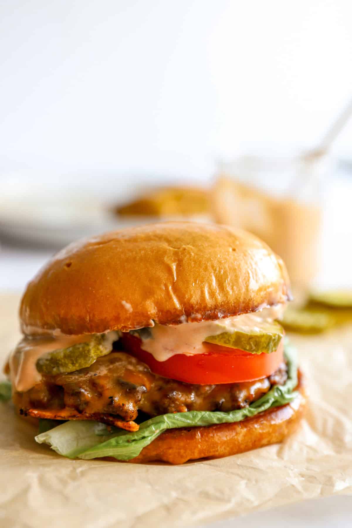 A smash burger with lettuce, tomatoes, pickles, and burger sauce. 