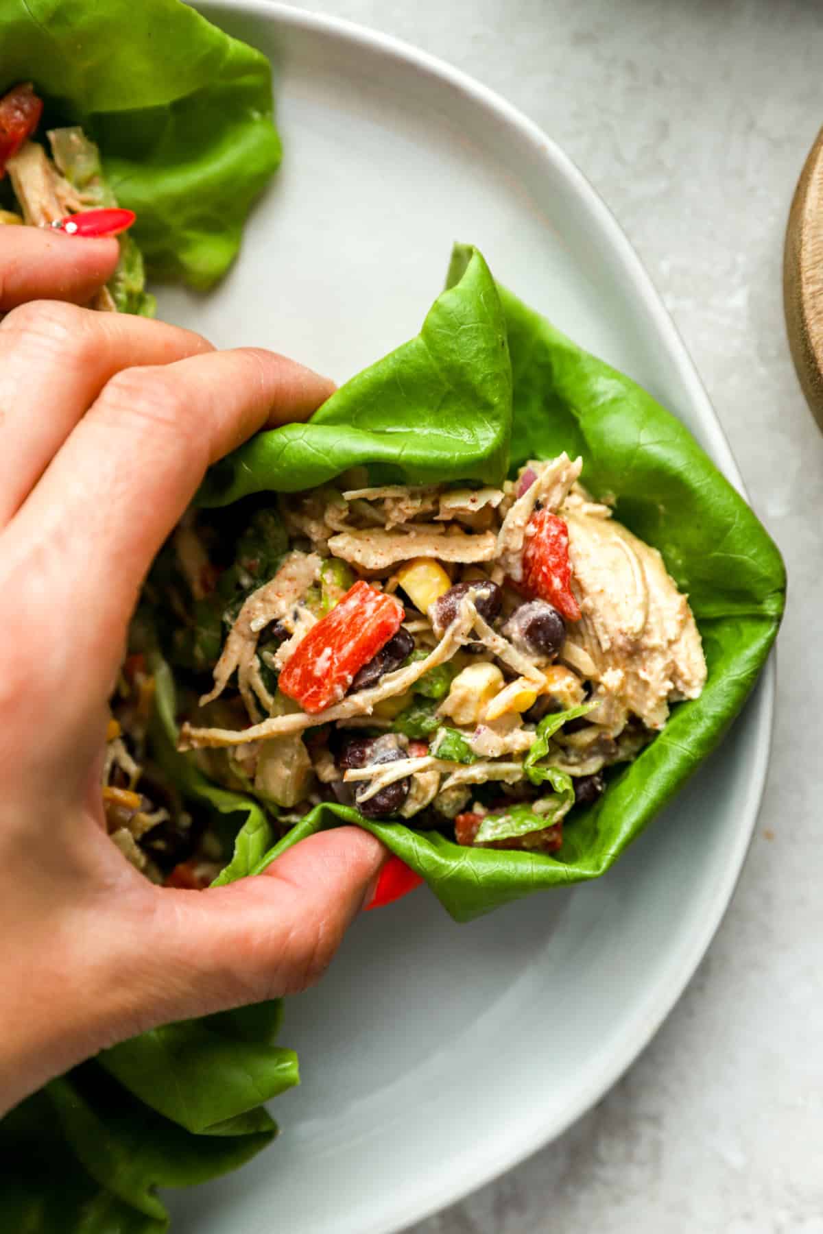 A hand holding a chicken taco salad lettuce wrap. 