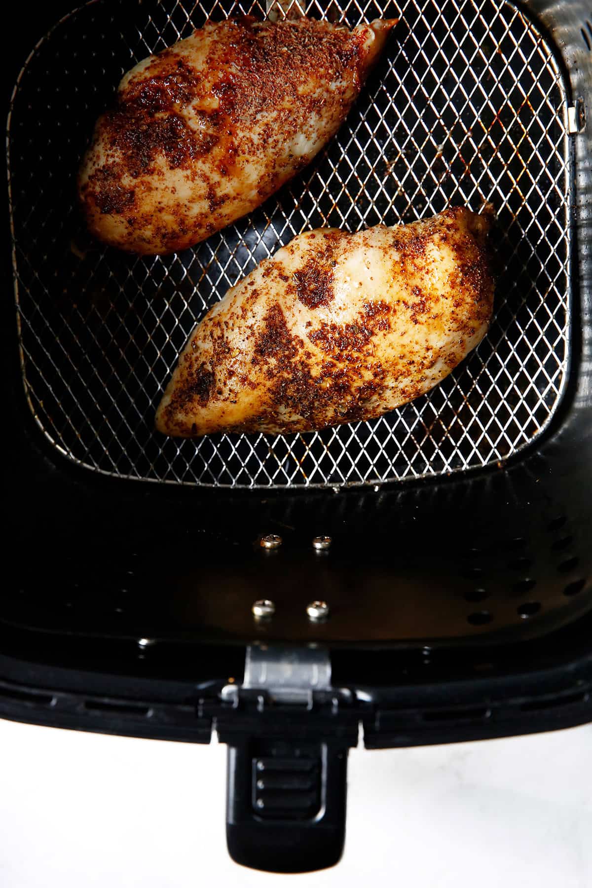 Cooked seasoned chicken breasts in an air fryer.