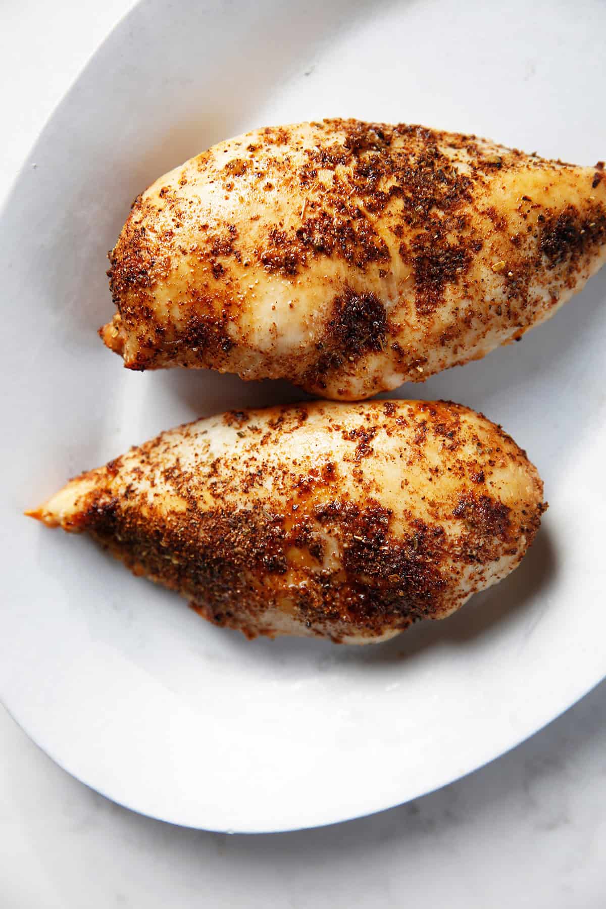 Two cooked air fryer chicken breasts on a plate. 