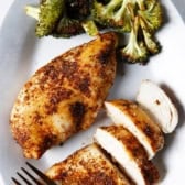 A plate with broccoli, a whole air fryer chicken breast, and chicken pieces.