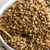 Close up view of a bowl of lentils with a spoon sticking out.