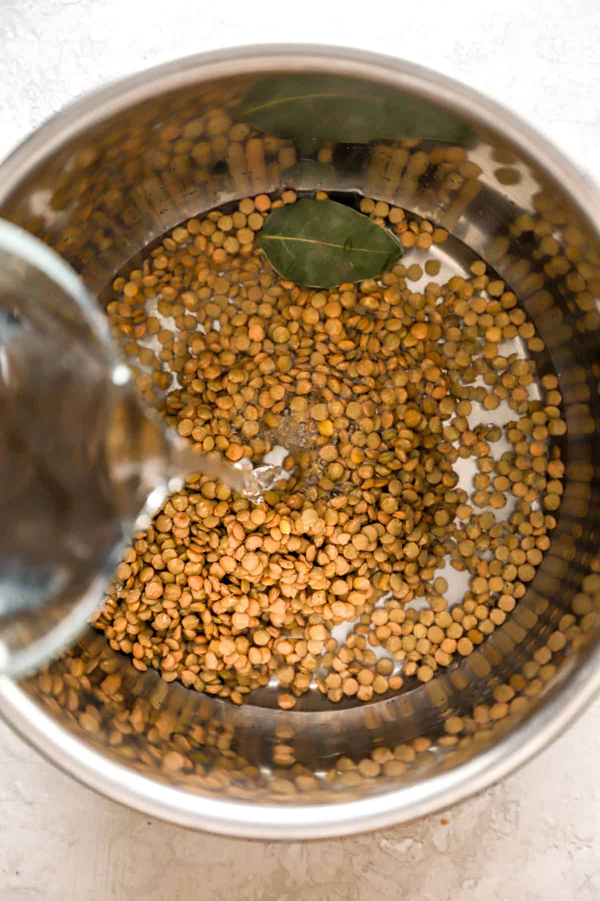 Water being poured into an Instant Pot with lentils. 