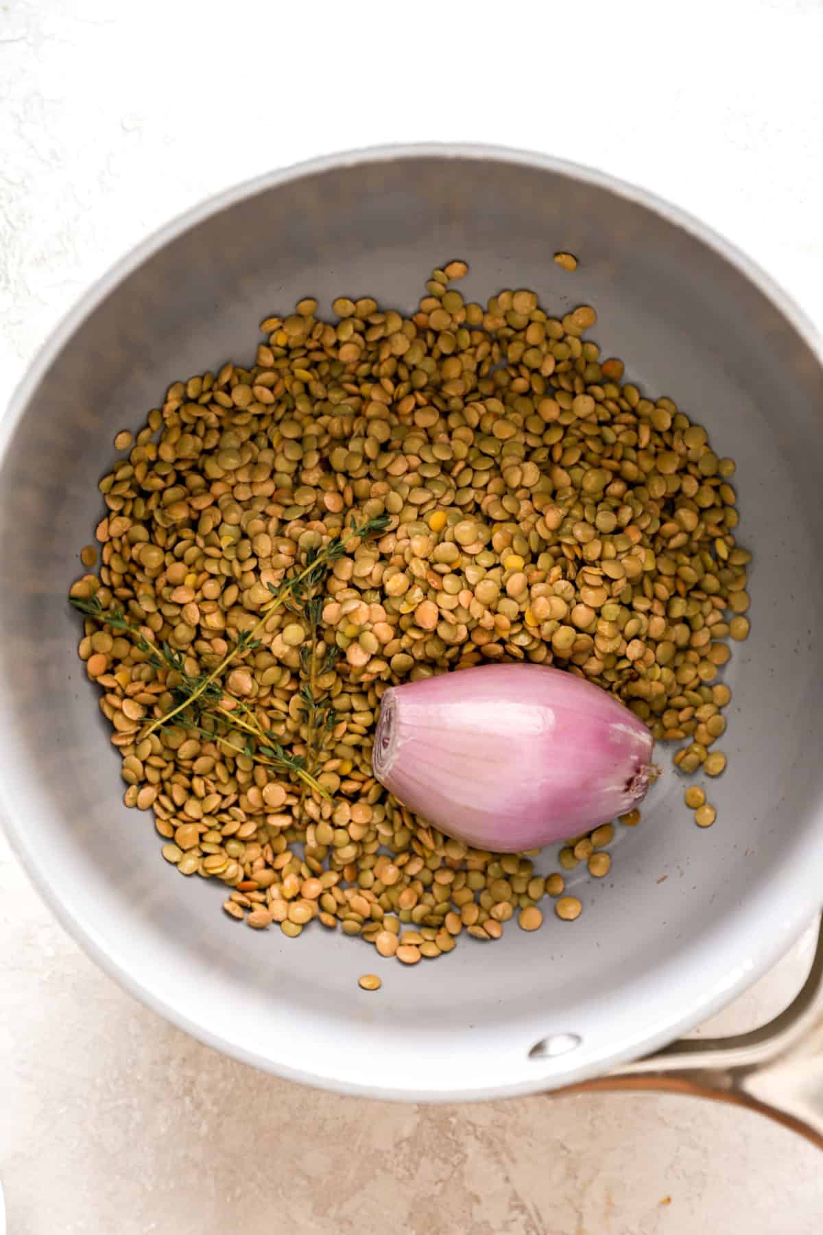 Dry lentils and a shallot in a pot. 