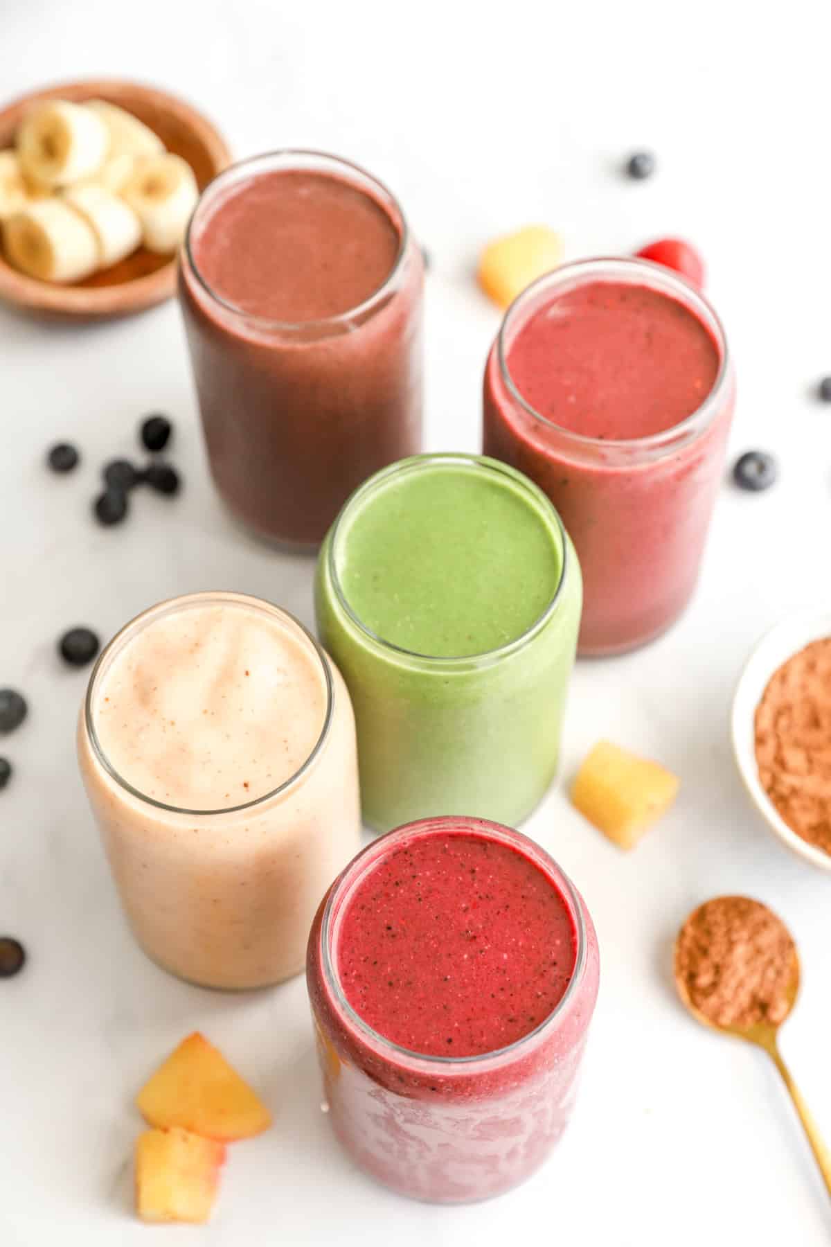 Overhead image of five glasses of smoothies with different flavors. 