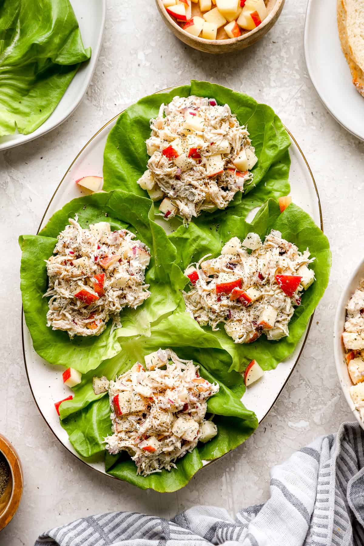 Ensalada de pollo de eneldo de manzana servido en cuatro tazas de lechuga de hoja de mantequilla. 