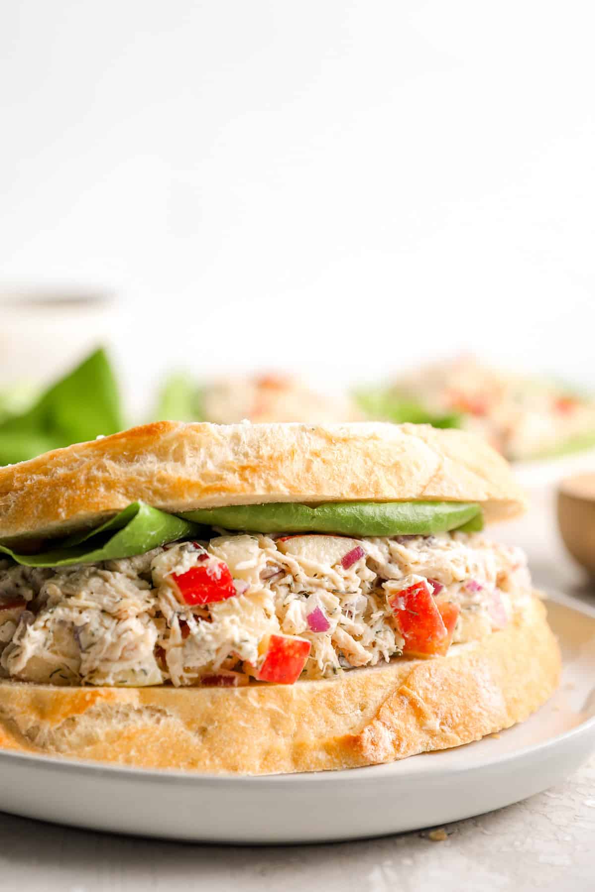 Ensalada de pollo de eneldo de manzana servido en un sándwich de pan blanco con lechuga de hoja de mantequilla. 