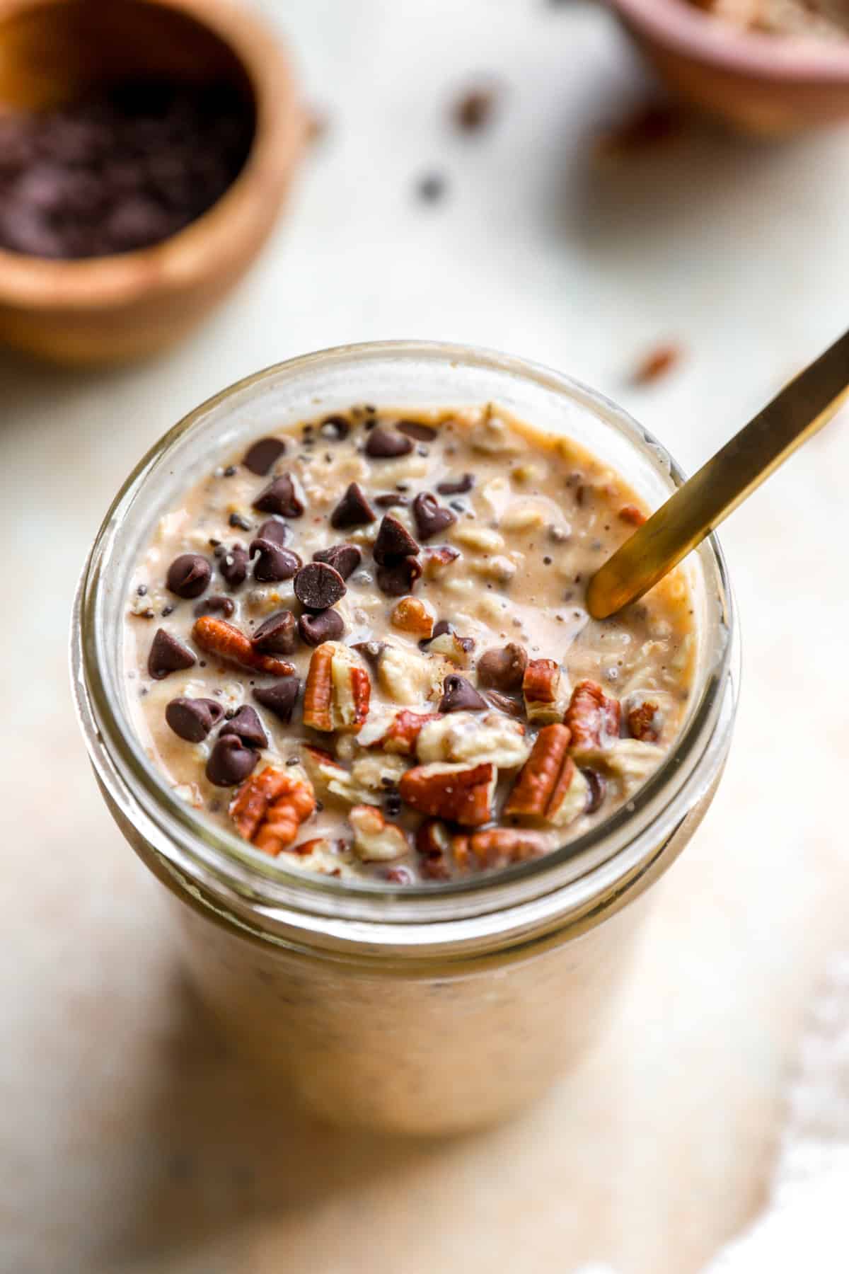 A spoon sticking out of a jar of pumpkin overnight oats. 