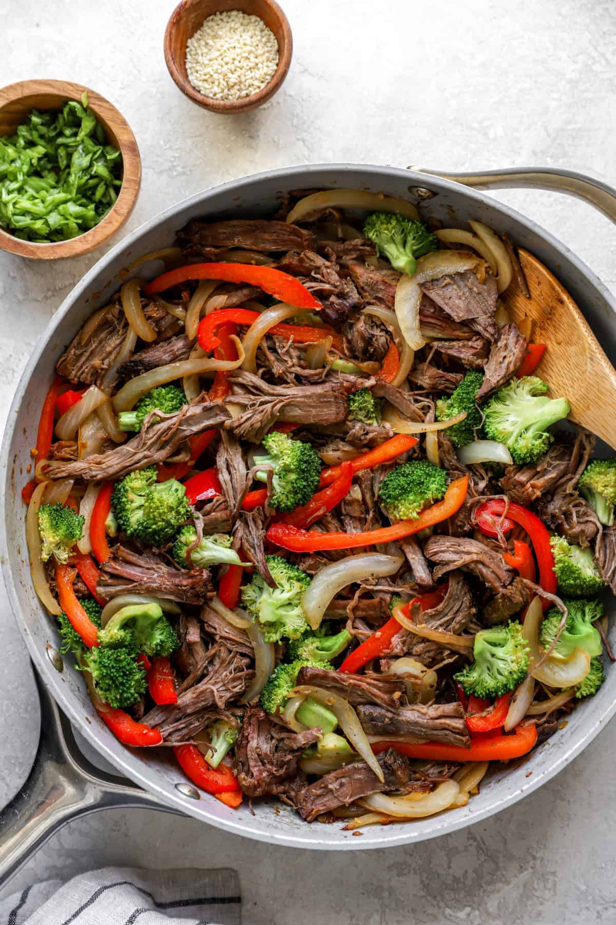 Peppers, broccoli, and beef cooking in a skillet. 