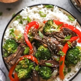 A bowl of slow cooker Asian beef and peppers over rice.