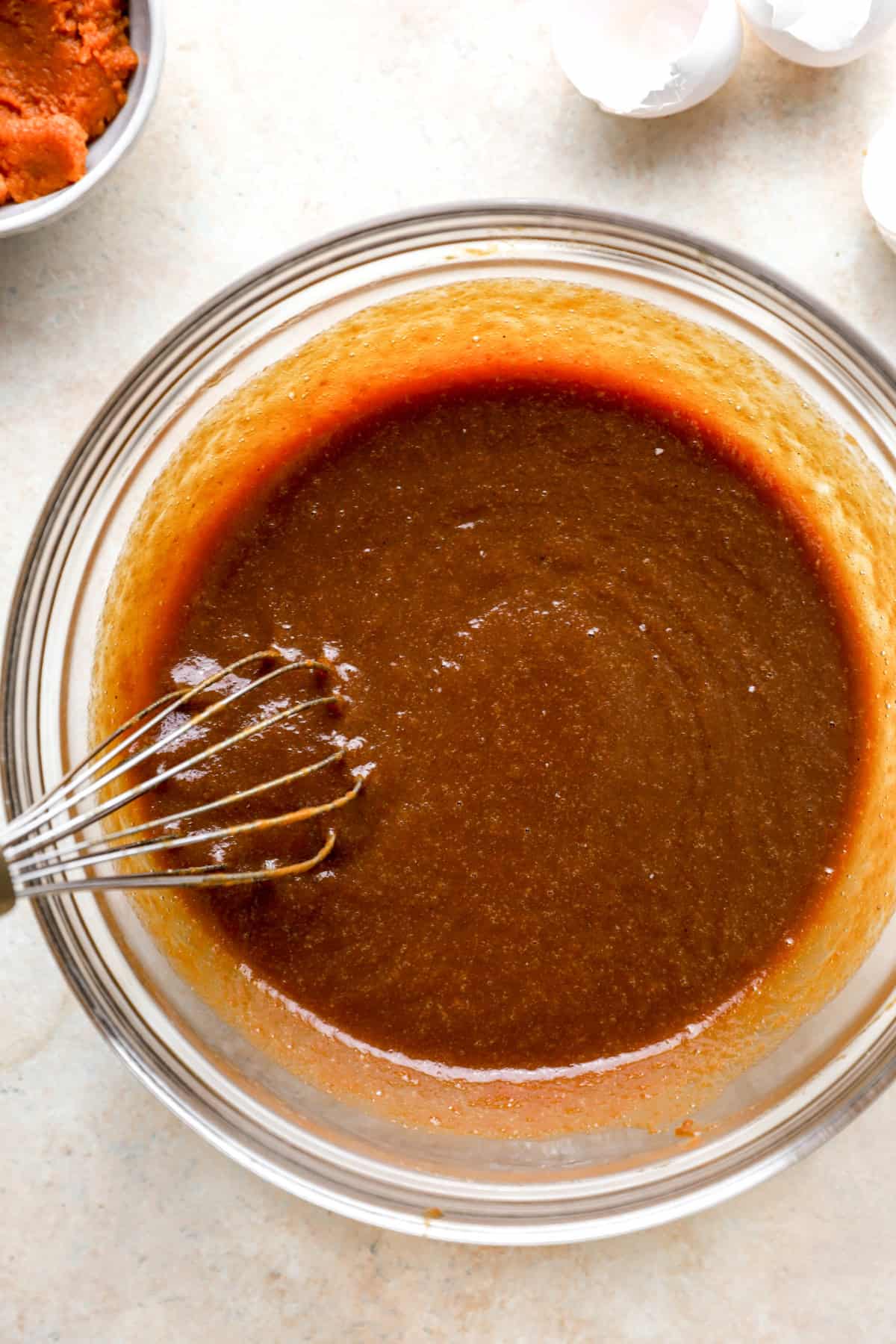 Wet ingredients for pumpkin cake being whisked in a bowl.