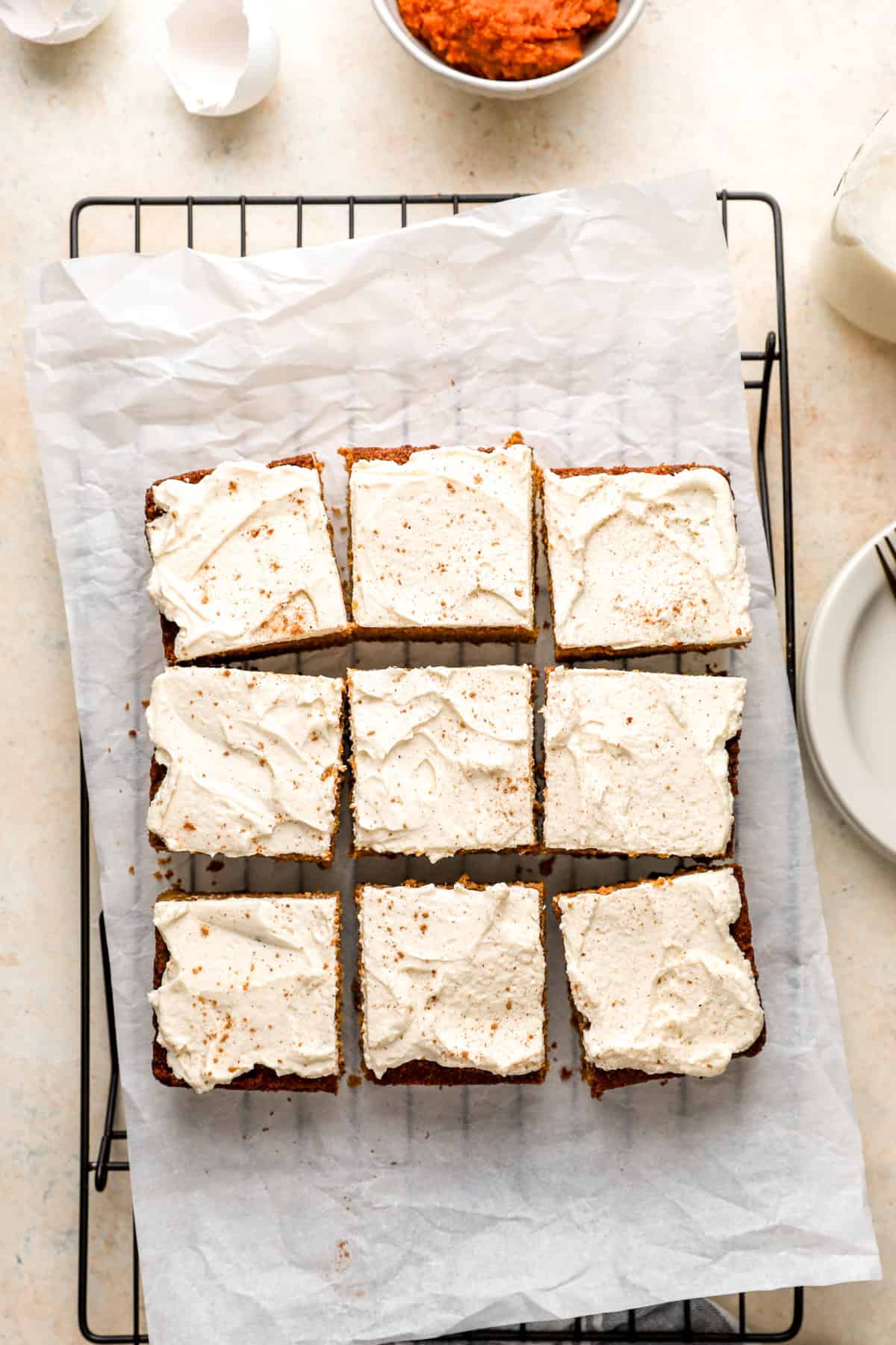 Nine slices of pumpkin cake topped with cream cheese frosting. 