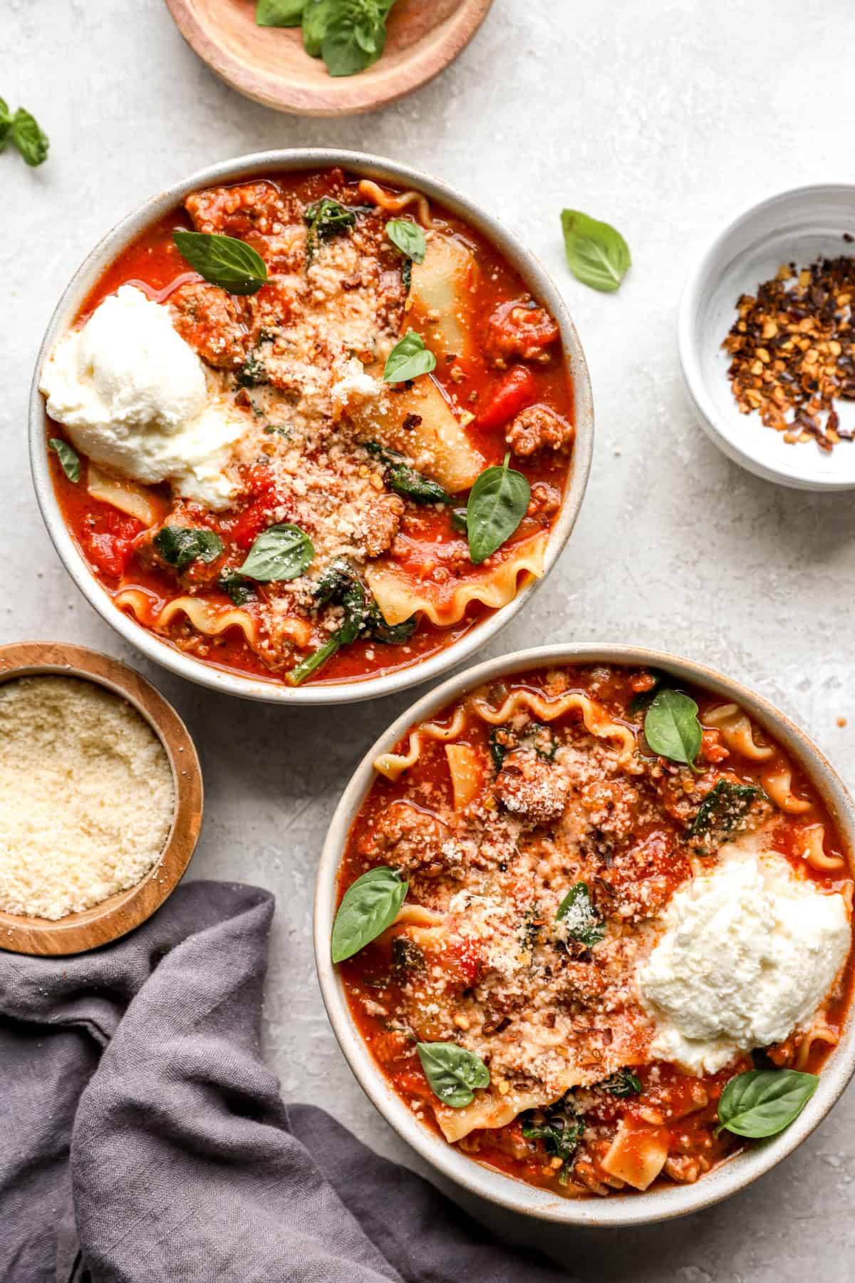 Two bowls of lasagna soup topped with cheese. 