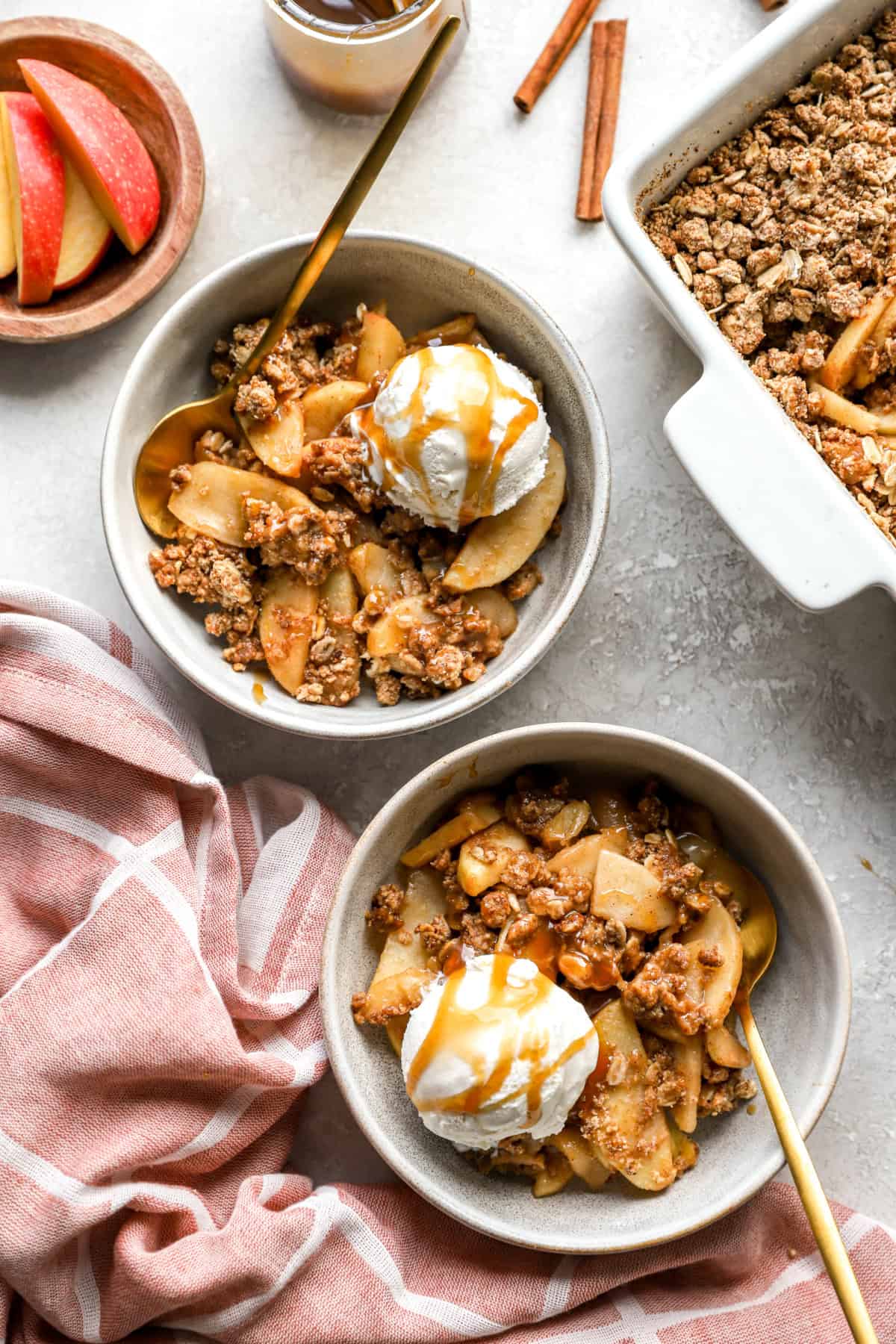 Two bowls of easy apple crisp with ice cream and caramel. 