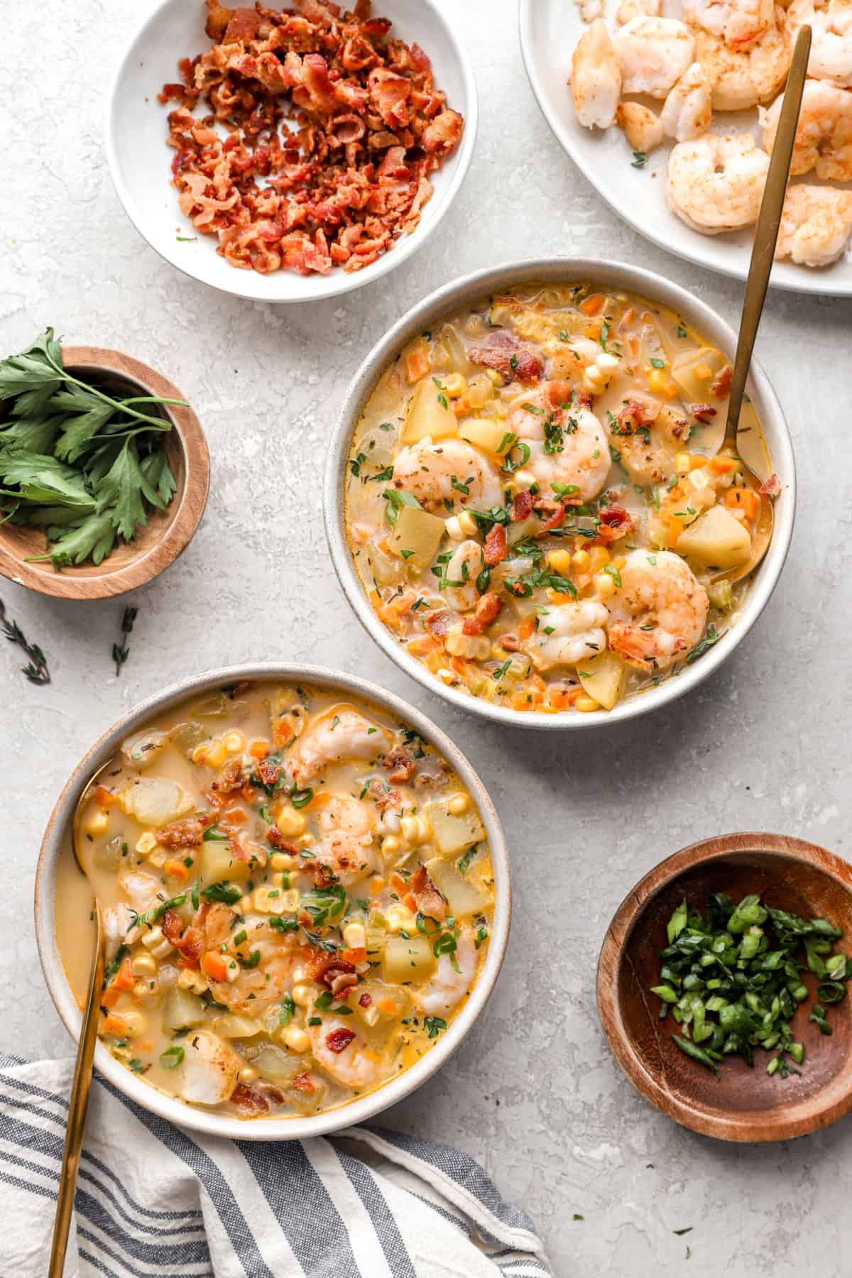 Two bowls of potato chowder with shrimp, bacon, and corn. 