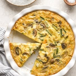 Overhead image of a hash brown crust quiche with a slice cut.