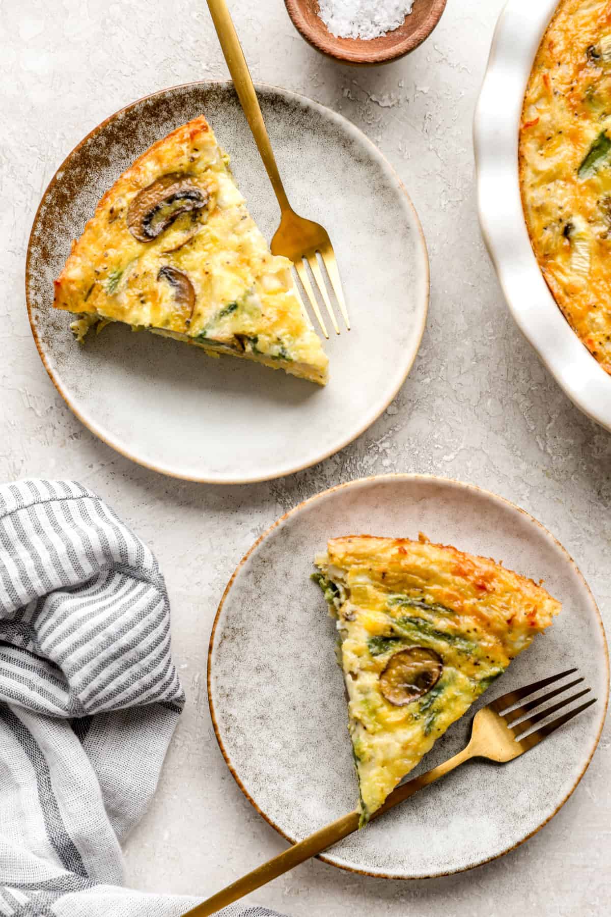 Two slices of hash brown quiche on plates. 