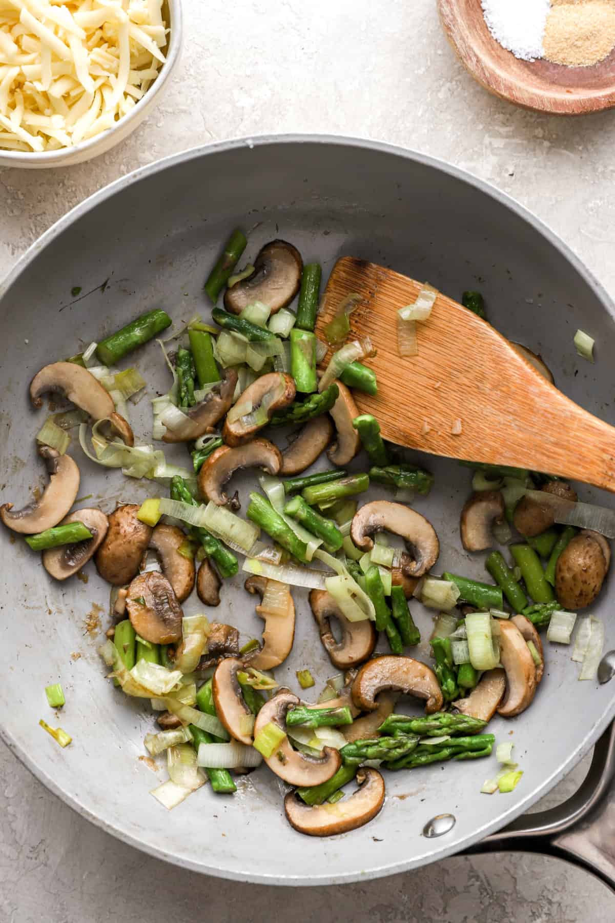 Asparagus and mushrooms sautéing in a skillet.