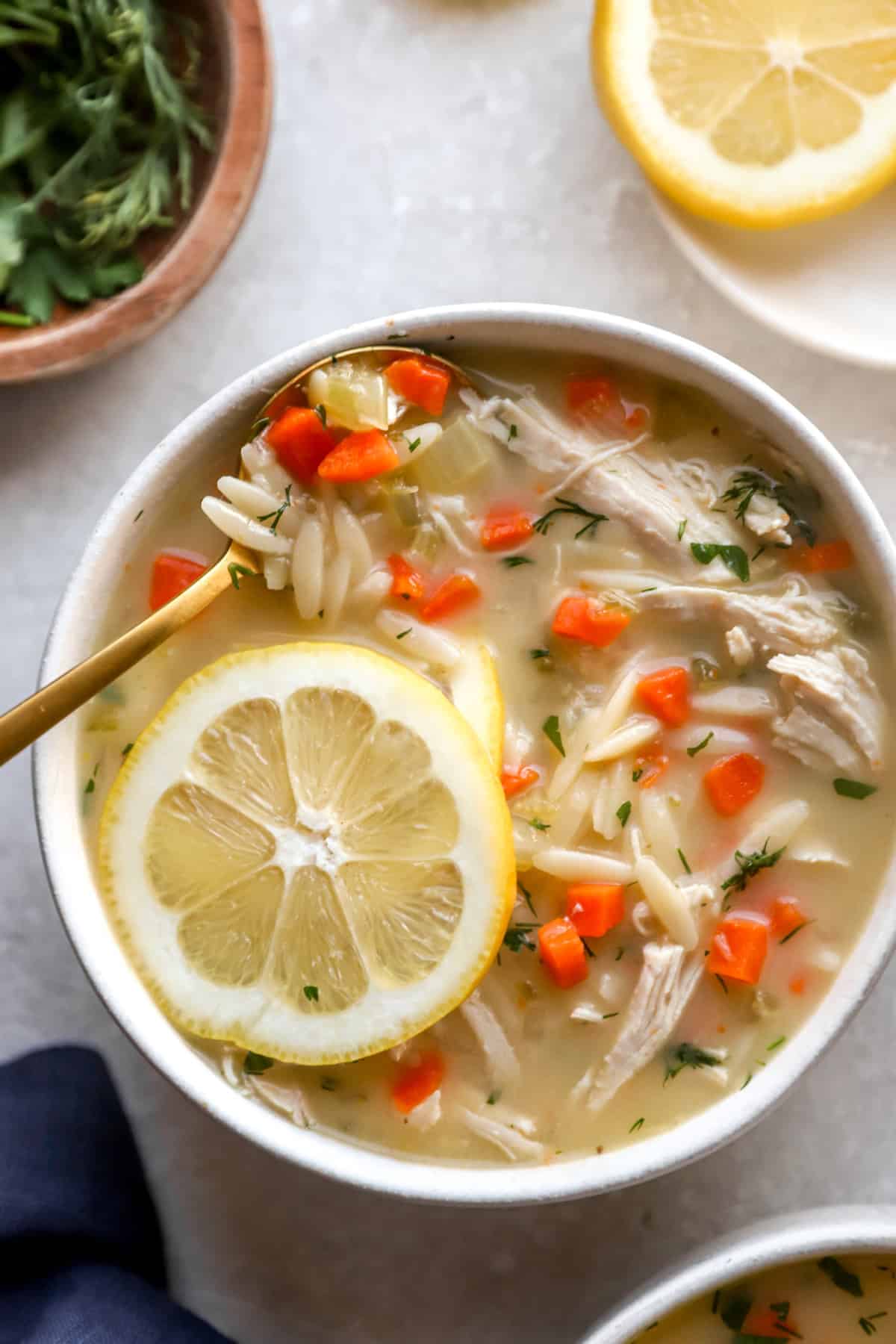 A bowl of avgolemono soup topped with a lemon slice.