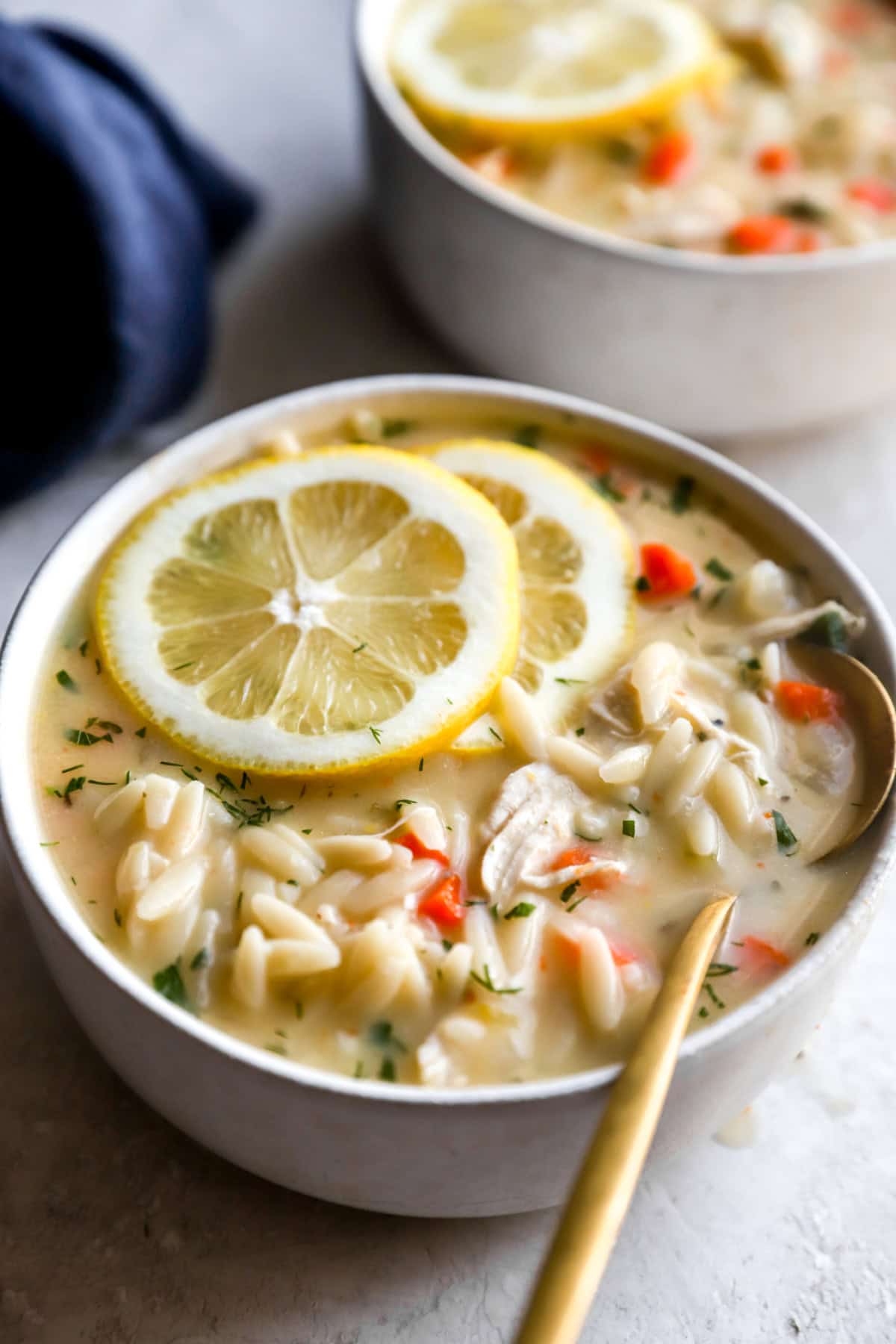 A bowl of Greek avgolemono soup topped wiht lemon slices. 