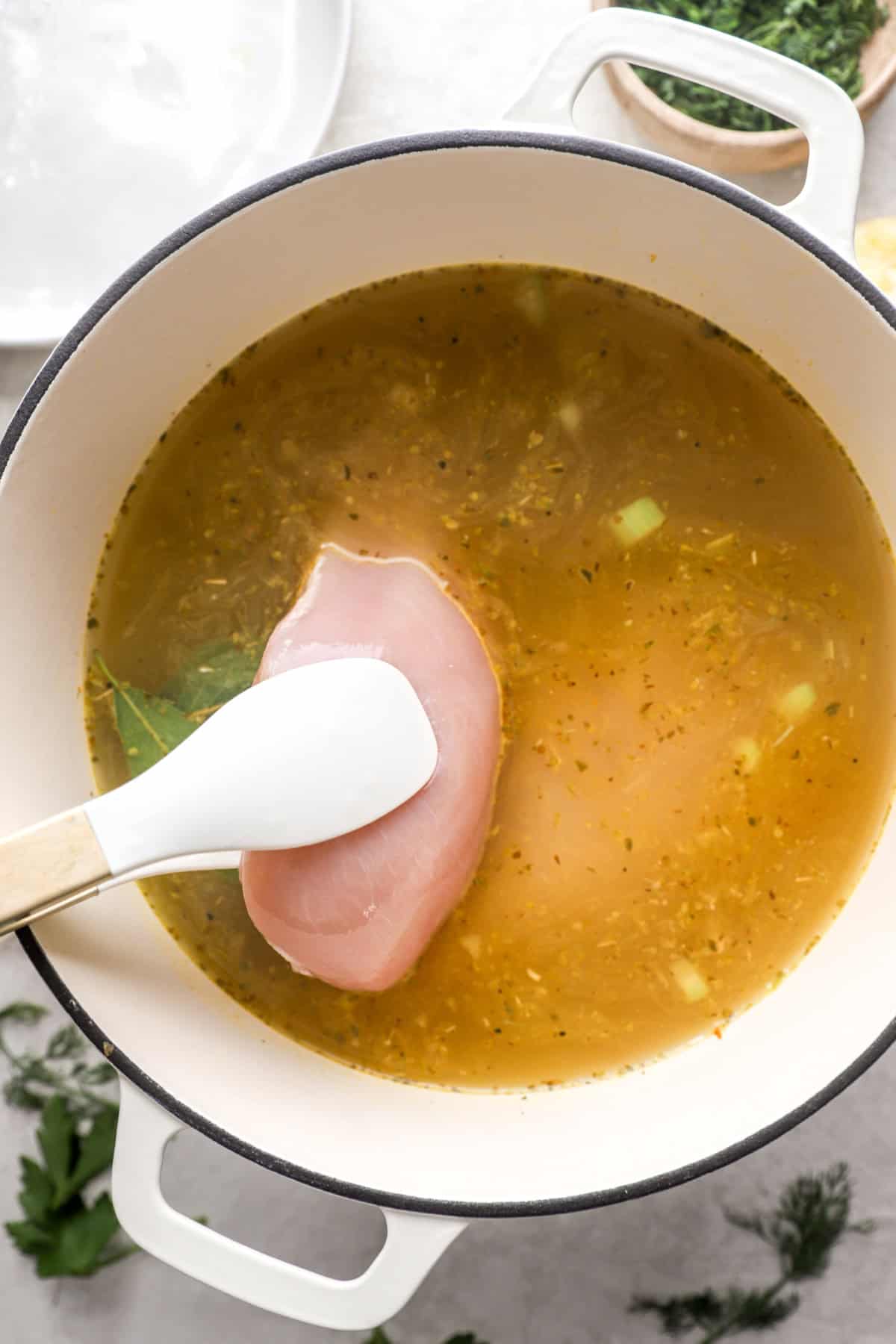 Chicken being added to a pot of avgolemono soup.