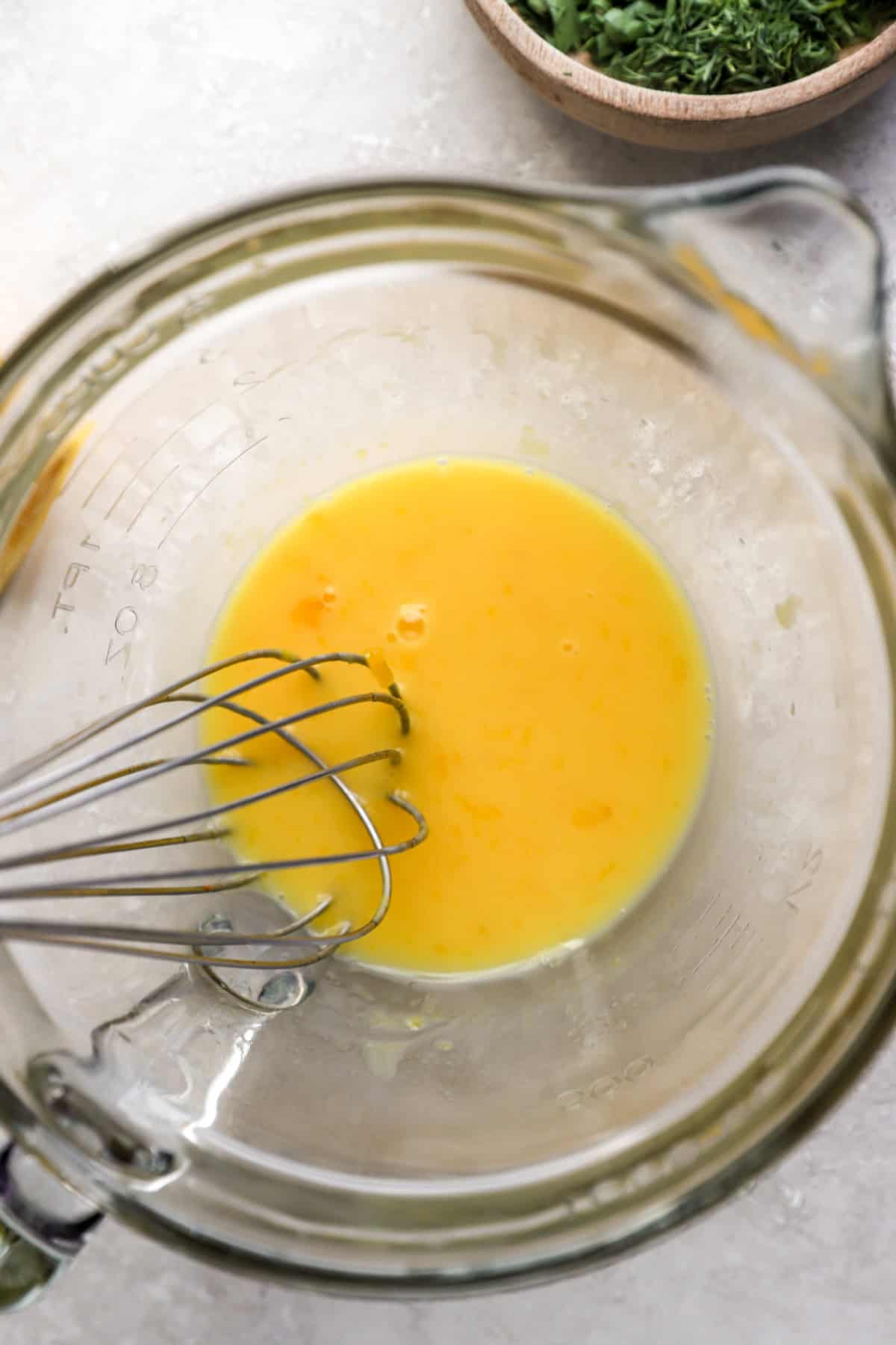 Avgolemono sauce being whisked in a bowl. 