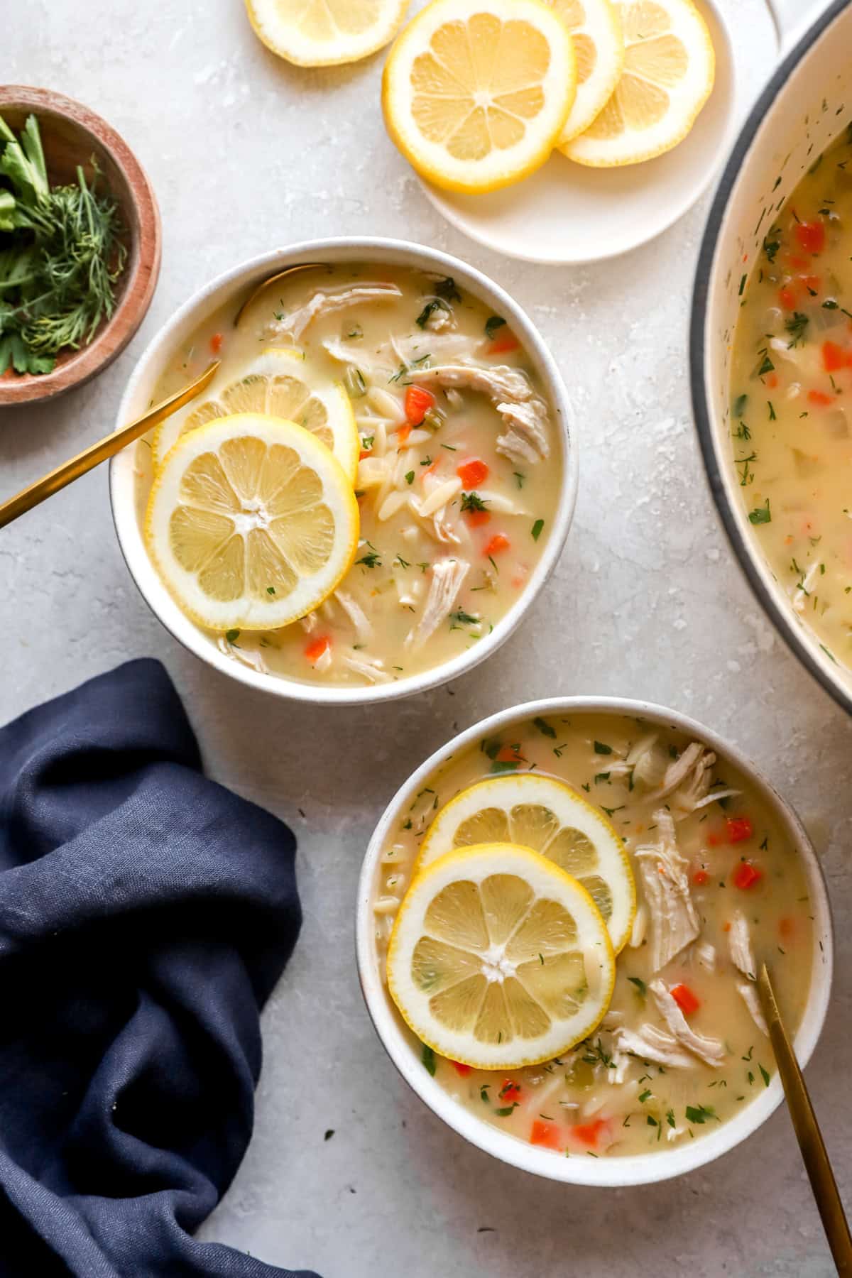 Two bowls of Greek avgolemono soup topped with lemon slices. 