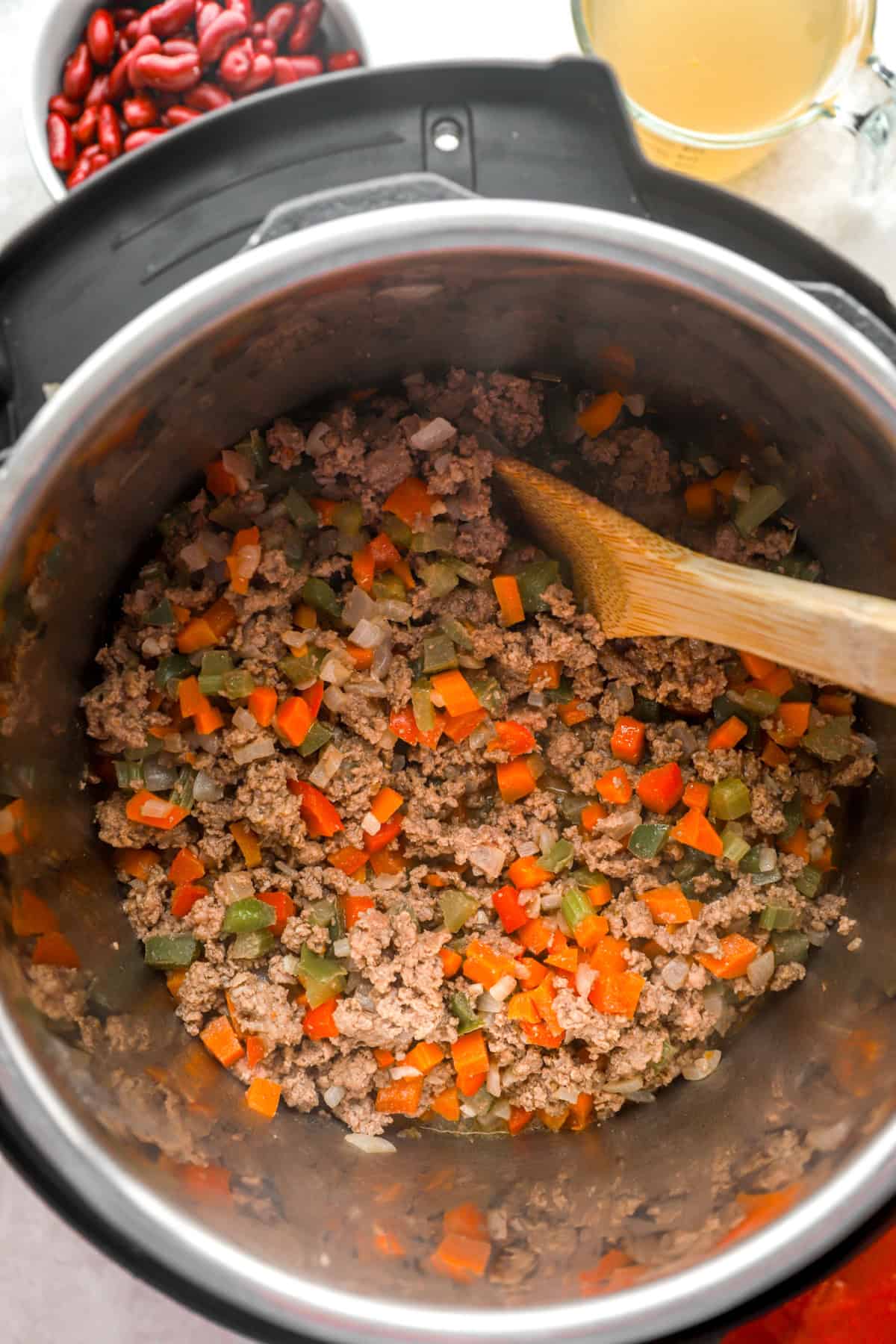 Ground beef being browned with vegetables in an Instant Pot. 